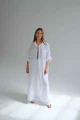 Camisola larga blanca de lino italiano, con corte fluido, cuello camisero, mangas 3/4 con trabilla y dos bolsillos de parche en el pecho.