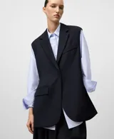 Chaleco sastrero sin mangas, color azul marino, con solapas de traje, cierre frontal de botón oculto y bolsillos de vivo en el pecho y la cadera. Presenta aberturas laterales y espalda corta.