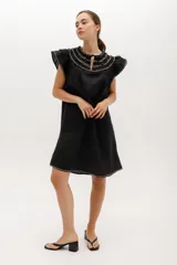 Vestido corto celeste de lino, corte suelto, con cuello redondo con volados y lazo, mangas cortas con volados.