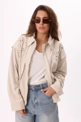 Campera color crema tipo gamuza con cierre frontal, cuello clásico, mangas largas y calados florales en hombros y espalda.