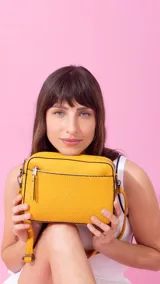 Bandolera color beige con diseño geométrico en el frente, cierre superior y correa larga regulable.