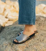 Sandalias bajas de cuero vacuno color negro, con suela de goma y horma de punta redonda. Producto de horma chica, se recomienda pedir un talle más.