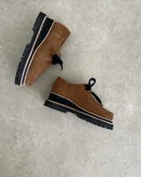 Zapato mocasín acordonado de cuero color marrón, con suela track negra y detalle de ribete color crema.