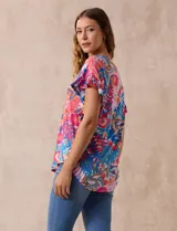 Blusa estampada con motivos florales en tonos rosa, azul y naranja. Tiene cuello en V y mangas cortas con volados.