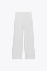 Pantalón largo de corte amplio, color blanco con finas rayas verticales negras, cintura elástica con cordón ajustable.