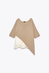Top color beige de tejido de punto con mangas 3/4 y bajo asimétrico. Detalle de tejido combinado doble capa con encaje blanco en el ruedo.