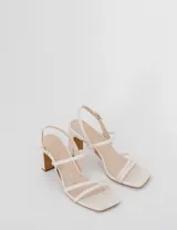 Sandalias de tacón color blanco con tiras finas y cierre con hebilla en el tobillo.