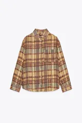 Camisa de mujer confeccionada en ramio 100% con estampado a cuadros en tonos beige, marrón y celeste. Tiene cuello solapa, manga larga con puños, bolsillo de plastrón en el delantero, bajo redondeado y cierre frontal con botones.