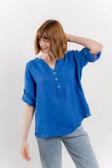 Camisa azul de lino con escote en V abotonado, bolsillo frontal y mangas 3/4 con trabilla.