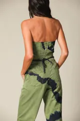 Pantalón de pierna ancha color verde con estampado batik en negro, de tiro bajo, cintura elástica con cordón ajustable, bolsillos laterales y aberturas laterales en el ruedo.