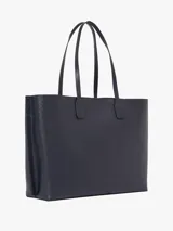 Bolso tipo tote Tommy Hilfiger color azul marino con diseño de monograma TH en relieve. Incluye monedero extraíble con cremallera y cierre magnético. Tiene doble asa superior, dos compartimentos principales y un compartimento interior con cremallera.
