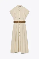 Vestido midi camisero color beige, confeccionado en lino. Presenta cuello solapa, mangas cortas con vuelta, jaretas delanteras, bolsillos laterales ocultos en costura, cierre frontal con botones y cinturón trenzado marrón.