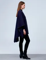 Ruana blanca de tejido suave, con ribete de eco cuero negro en los bordes y cierre frontal con botones metálicos dorados.