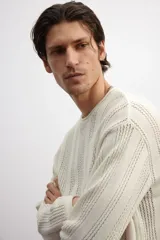 Buzo color crema en punto pointelle de mezcla de algodón, lino y viscosa. Modelo de hombros caídos con cuello redondo y bajo recto. Borde enrollado en cuello, puños y bajo.