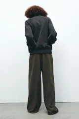 Pantalón de vestir color verde oscuro, de tiro alto con trabillas y pinzas delanteras. Presenta bolsillos laterales y falsos bolsillos traseros de vivo.
