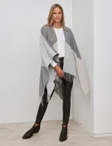 Ruana tejida colorblock en tonos grises y beige, con terminación de flecos en el ruedo.