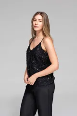 Musculosa negra con lentejuelas, breteles finos regulables y escote en V. De calce relajado y tiro a la cadera.