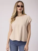 Blusa color beige de corte holgado, con cuello redondo y mangas cortas con dobladillo.
