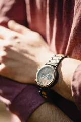 Reloj de pulsera Chenaut Aurum para hombre, con caja de acero inoxidable negra y esfera de madera de zebrano. La malla es de acero inoxidable negra con detalles en madera de bambú. Tiene cronógrafo, indicador de 24 horas y fechador.