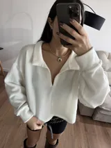 Buzo blanco de tejido de punto con cuello polo y mangas largas.