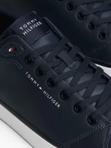 Zapatillas de corte bajo Tommy Hilfiger confeccionadas en una mezcla de piel color azul marino. Presentan un diseño atemporal con cordones al tono, suela de goma vulcanizada blanca y detalles distintivos de la marca, incluyendo el logo en el lateral, la lengüeta y el talón bordado.