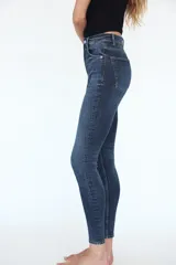 Jeans skinny de tiro alto en denim azul oscuro, con cinco bolsillos y cierre frontal con cremallera y botón metálico.