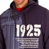 Buzo hoodie Caterpillar azul marino con capucha ajustable con cordones bicolor, bolsillo tipo canguro, puños y dobladillo acanalados. Estampado frontal con el año 1925 y texto alusivo a la historia de la marca. Logo de Caterpillar estampado en la manga izquierda.