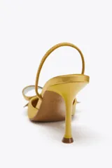 Zapato de tacón destalonado color dorado, con efecto satinado, punta fina, tira trasera elástica y maxi lazo decorativo en la parte delantera.