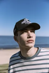 Gorra negra de 5 paneles con cierre snapback ajustable y bordado frontal con logo.