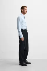 Camisa blanca de corte regular, cuello italiano, manga larga con puños abotonados y cierre frontal con botones.
