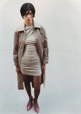 Vestido corto color beige, de corte ajustado, con escote asimétrico y detalle de frunces.