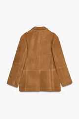 Blazer de cuero color marrón, con cuello solapa de muescas y manga larga. Bolsillos delanteros ocultos en costura y cierre frontal con botones.