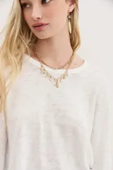 Remera blanca de algodón con calce relajado y cuello redondo. Tiene mangas largas que se ajustan hacia los puños.