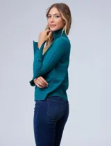 Polera de punto fino marca Nienty, color blanco, con cuello alto volcado y mangas largas con detalle de tajo en los puños.