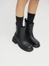 Botas negras de cuero con diseño floral en relieve, corte Chelsea, elásticos laterales, plataforma delantera de 2cm y tacón de 5,5 cm.