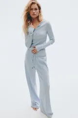 Remera ajustada de punto acanalado suave, color celeste, con manga larga, cuello redondo ribeteado en picot y tapeta de botones.