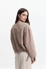Campera corta color verde militar, sin cuello, con cierre frontal y elástico en la cintura. Tiene bolsillos amplios y mangas largas con puños elásticos.