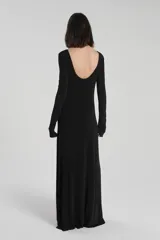 Vestido largo negro de jersey texturizado con spandex y acabado brillante, corte ajustado, escote redondo, manga larga, abertura lateral a la altura de la cadera con detalle metálico.