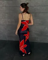Vestido largo negro con estampado de flores rojas, de tirantes finos y corte al cuerpo.