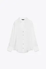 Camisa blanca de satén con cuello solapa, escote en pico, manga larga y cierre frontal con botones metálicos.