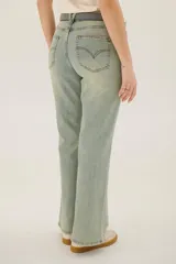 Pantalón de jean azul de corte acampanado, con bolsillos delanteros y traseros, y detalle de cuero sintético en la cintura.