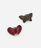 Set de dos pinzas para el pelo, una con forma de mariposa transparente color gris oscuro y otra con forma de corazón color rojo.