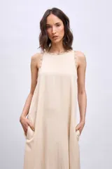 Vestido largo color crema, de corte recto y sin mangas, con detalle de bordado calado en cuello y sisas.