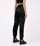Pantalón jogger negro de poliéster con rayas laterales y cadena decorativa.