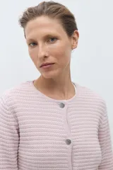 Chaqueta de punto color celeste claro, de manga larga y corte ajustado, con cuello redondo y cierre frontal de botones metálicos plateados. El tejido presenta un patrón texturizado horizontal.