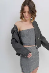 Chaqueta tipo biker de cuero ecológico (PU) color marrón con acabado desgastado, cuello Mao con broches metálicos, cierre frontal y bolsillos con cremallera.