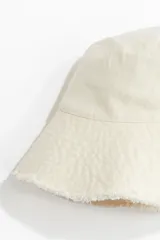 Sombrero tipo bucket de denim color crudo con ala ancha y acabado desflecado. Forro interior de algodón.