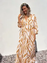 Vestido largo tipo túnica con estampado de cebra en tonos beige y crudo, con cuello en V y mangas 3/4.