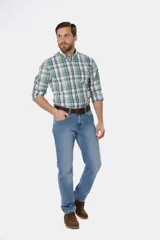 Pantalón de jean azul oscuro de corte recto y tiro medio. Incluye cinturón de cuero marrón y botas de gamuza marrón.