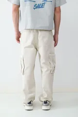 Pantalón cargo beige de corte recto confeccionado en 100% algodón, con múltiples bolsillos delanteros, laterales y traseros.